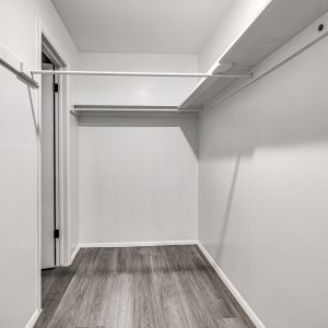 Empty walk-in closet with white wire shelving and wood-look flooring