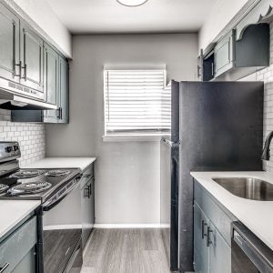 Galley kitchen with white subway tile backsplash, black appliances, and white countertops