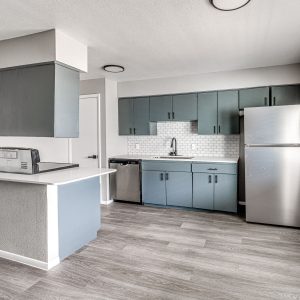 Kitchen with blue cabinets, stainless steel refrigerator and dishwasher, subway tile backsplash, and wood-look flooring
